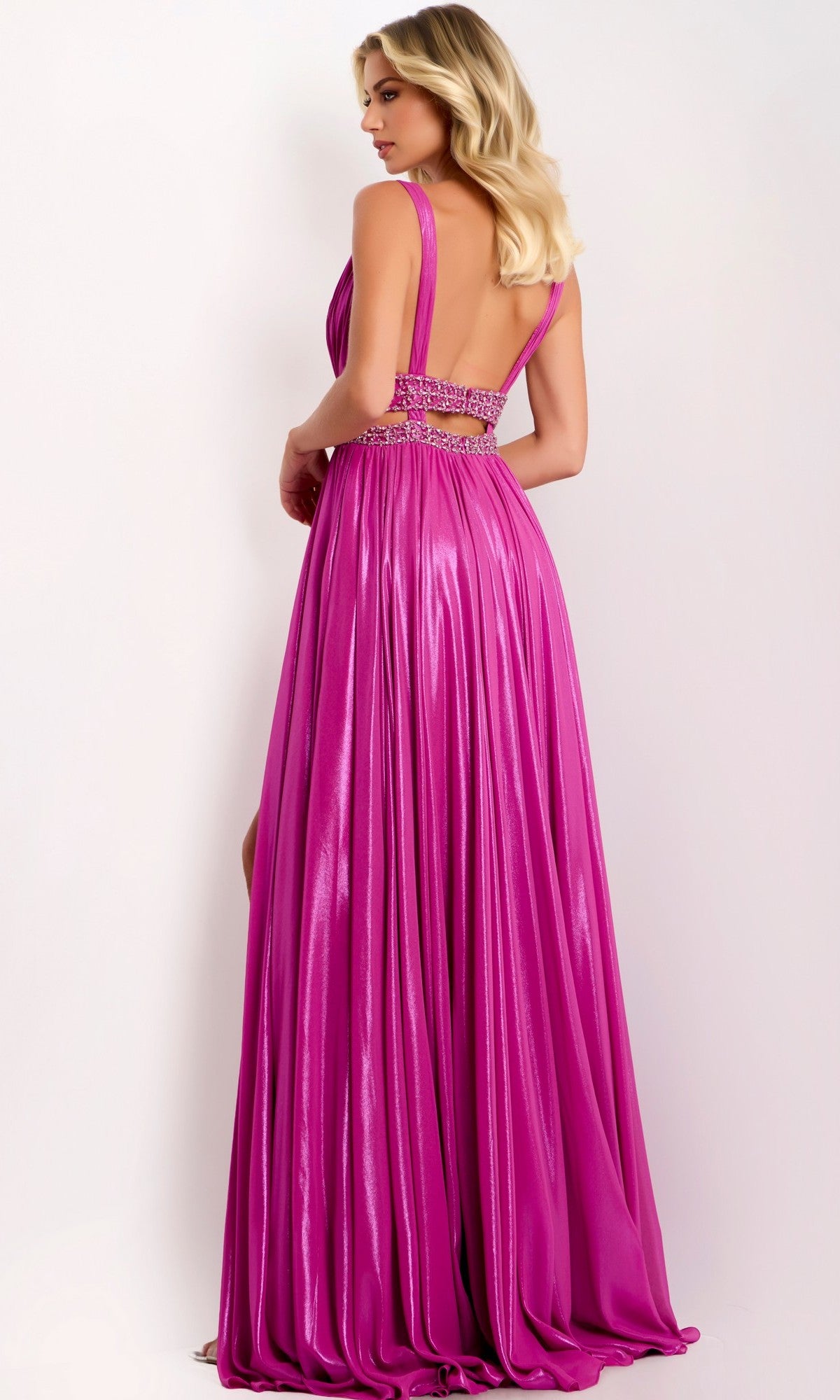 A woman stands against a light background wearing the Jovani 42817 long prom dress, which is sleeveless with a shiny magenta metallic finish, beaded detailing, and an open back.